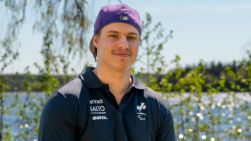 Nemo Pajula poseeraamassa kameralle ulkona auringossa. Taustalla vihreää kasvustoa ja vesistö.